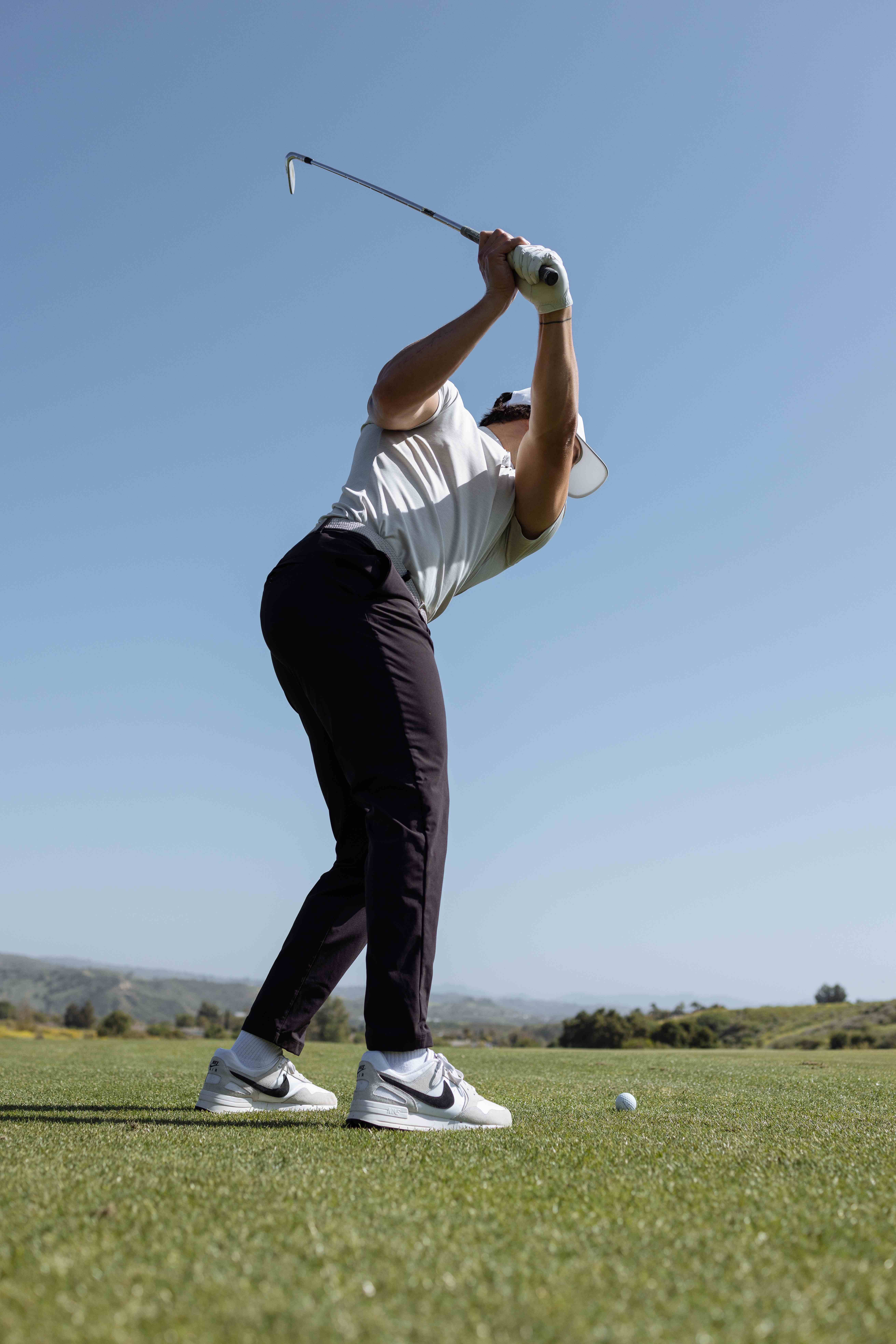Golfer holding a balanced position at the top of the backswing on a sunlit course